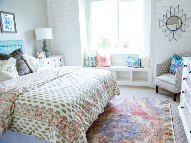 This guest bedroom is lovely with its pop of bright colors and shiplap window-seat. Millhaven Homes
