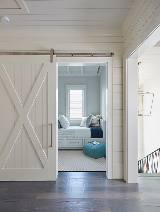 Shiplap and barn door. This white shiplap barn door opens to reveal a kids' bedroom filled with white built-in beds with storage drawers. #whitebarndoor #shiplapbarndoor Hall features shiplap and bedrooms with barn door. #barndoor #shiplap shiplap-and-barn-door