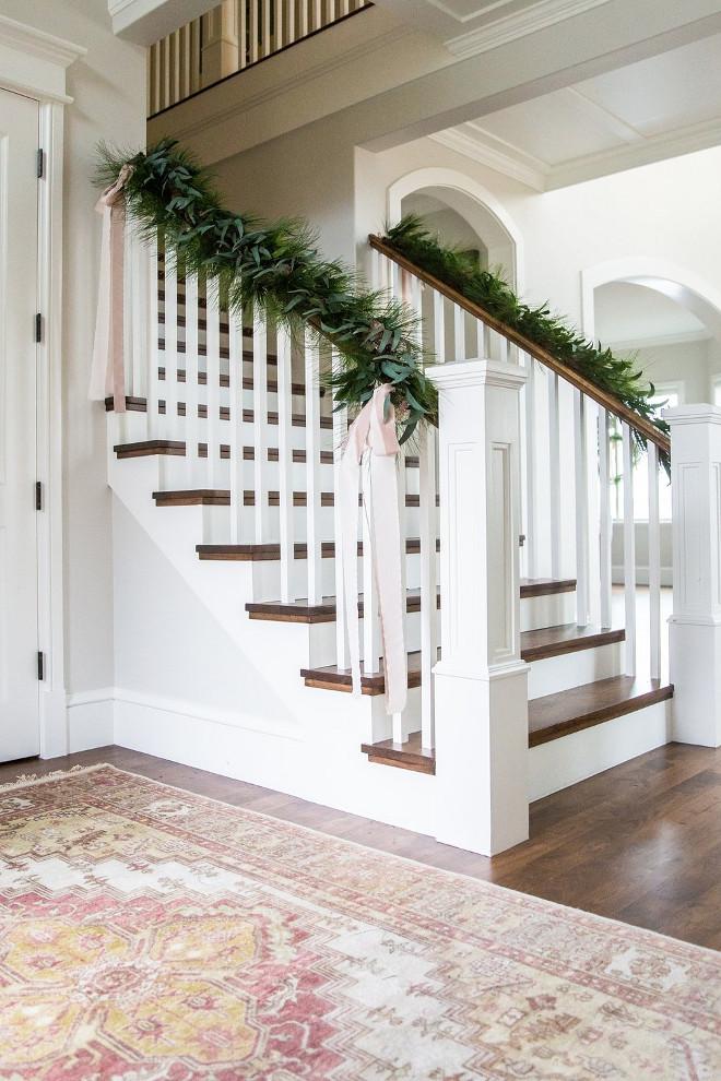 Staircase Christmas Decor. Banister Garland. Make sure you have wire cutters and floral wire to fasten your garland onto the the banister! We like to drape or have the garland follow the line of the banister rather than wrapping it around tightly. We add silk ribbon in our color palette in long bows to soften the look. Staircase Christmas Decor. Banister Garland ideas #StaircaseChristmasDecor #BanisterGarland Studio McGee