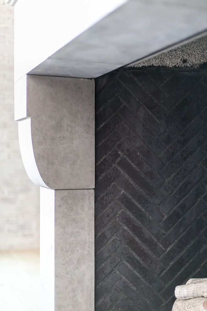 Dark grey firebrick. A close-up featuring the 1" x 9" dark grey firebrick hand laid in a herringbone pattern with the pre-cast limestone surround at the fireplace. #Darkgreyfirebrick #greyfirebrick Patterson Custom Homes