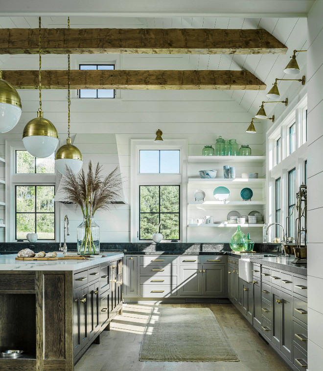 Farmhouse kitchen with vaulted ceiling, exposed beams, shiplap walls, shiplap ceiling, black metal windows, grey lower cabinets, open shelves, large oak island, brass cabinet hardware and brass lighting #Farmhouse #kitchen #farmhousekicthen #vaultedceiling #exposedbeams #shiplap #shiplapwalls #shiplapceiling #blackmetalwindows #greylowercabinets #openshelves #oakisland #Brasscabinethardware #brasslighting #farmhouseinteriors #kitchens #kitchen #interiors #interiordesign Roundtree Construction. TruexCullins Architecture + Interior Design