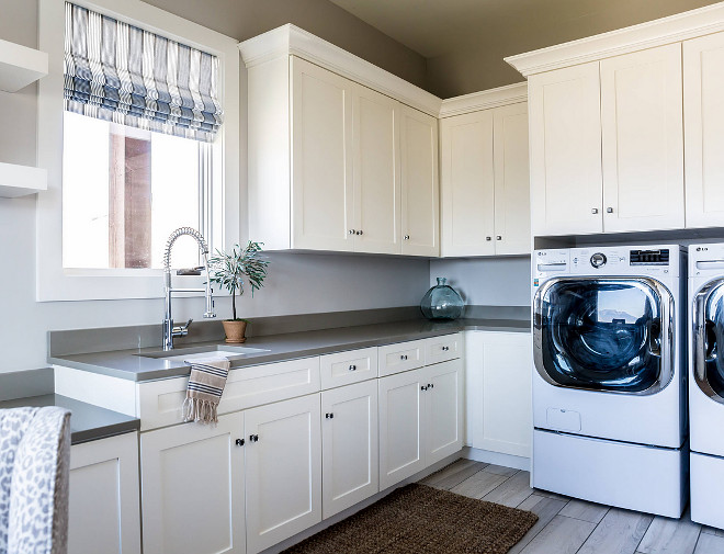 Laundry room. White laundry room with grey quartz countertop. Grey countertop contrasts perfectly with the white cabinets in this laundry room. White laundry room with grey quartz countertop, grey walls and side by side washer dryer. #Whitelaundryroom #laundryroom #greyquartzcountertop #sidebysidewasherdryer Timberidge Custom Homes