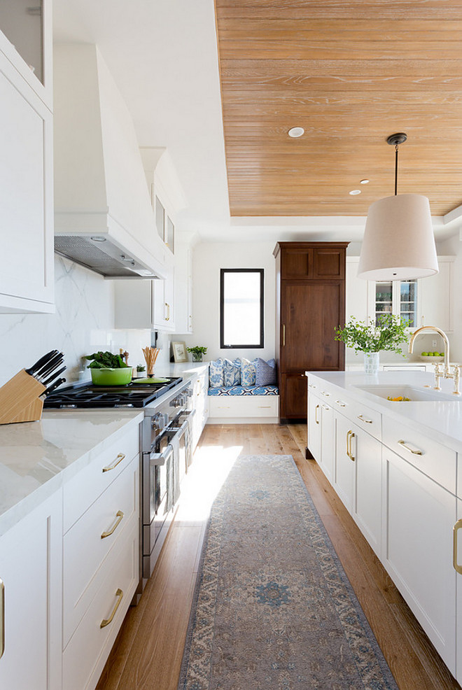 Modern Farmhouse Kitchen. Modern farmhouse kitchen with European White Oak Floors, white oak beadboard ceiling, brass cabinet hardware, black steel windows and a window seat. Wall paint color Baby's Breath by Benjamin Moore. Denton Developments. Amy Bartlam Photography.