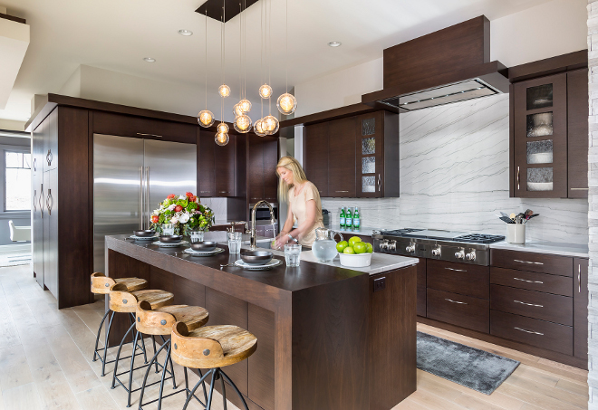 Modern kitchen design with sleek dark walnut cabinets. Kitchen Perimeter and Island Countertop/Backsplash: Polished 1- 1/4" White Macaubas Quartzite. Barstools are from Arteriors. Hendel Homes