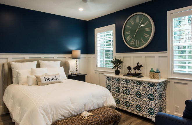 Navy bedroom with white board and batten wainscoting. Classic coastal bedroom color scheme with navy walls and white board and batten wall wainscoting #Classiccoastalcolorscheme #colorscheme #coastalcolors #bedroom #colors #navywalls #whiteboardandbatten #boardandbatten #wallwainscoting #wainscoting Waterview Kitchens