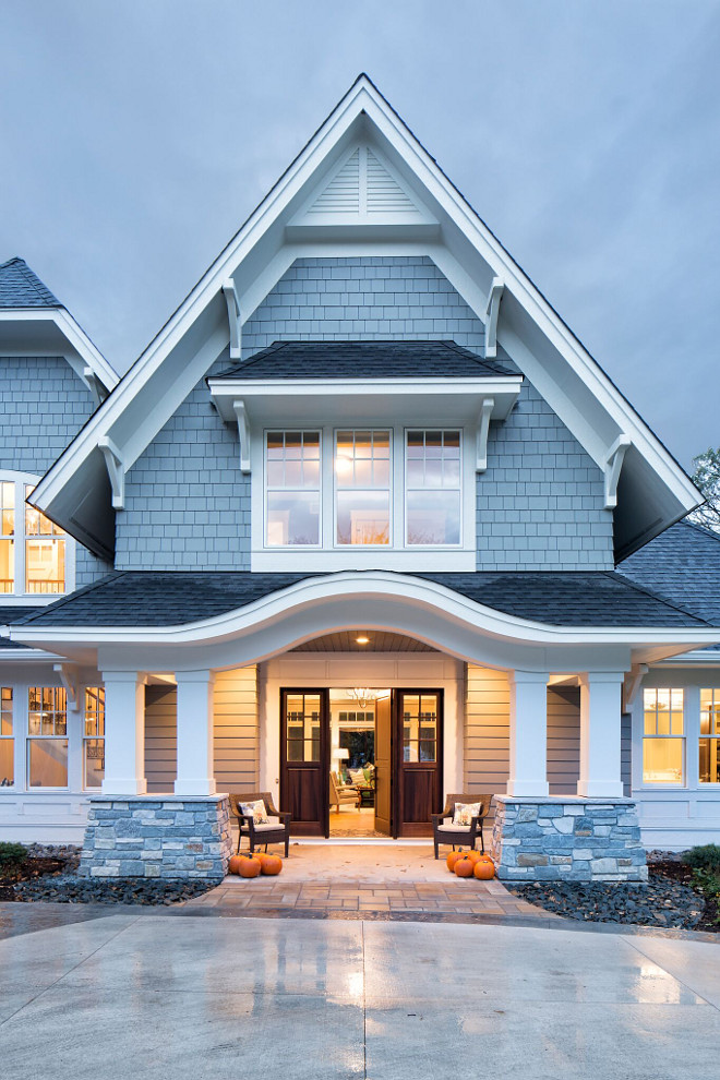 Grey Shingle Home with White Trim and Grey Stone Porch columns, The exterior is grand and inviting with an eyebrow arch over the covered front porch, Home exterior design Grey Shingle Home with White Trim and Grey Stone Porch columns #GreyShingleHome #WhiteTrim #GreyStone #Porchcolumns Grace Hill Design