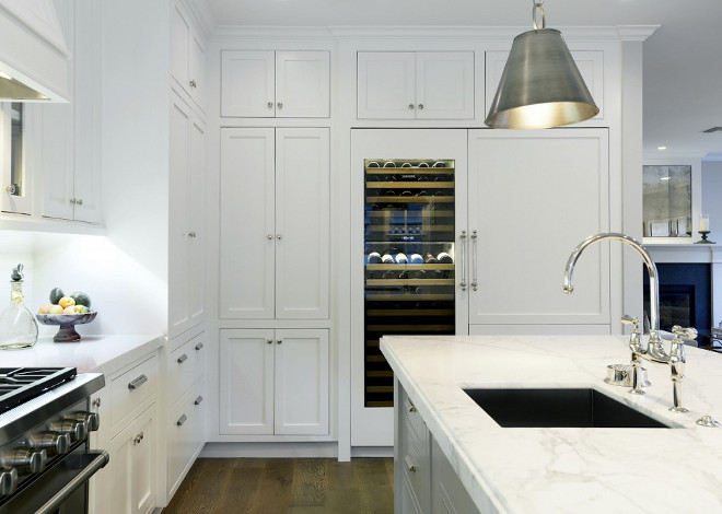 Kitchen Wine Cooler. Kitchen features white cabinets with white marble countertop and built in glass-door wine cooler #kitchen #winecooler Hamilton Architects