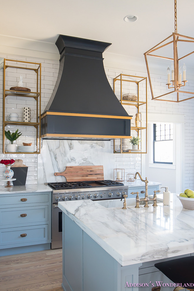 A black French kitchen hood, painted in Sherwin Williams Inkwell, is accented with gold trim and it's flanked by brass shelving. #blackhood #Frenchhood #Frenchkitchenhood #SherwinWilliamsInkwell #hoodgoldtrim Home Bunch's Beautiful Homes of Instagram @addisonswonderland