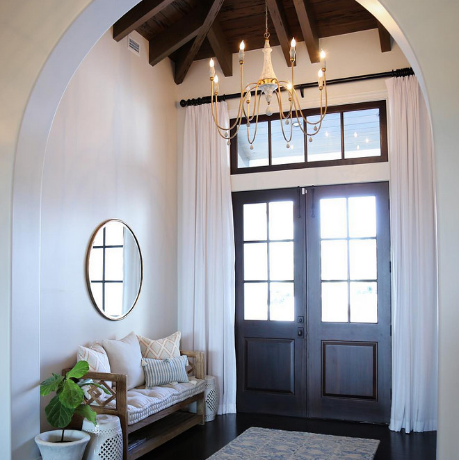 Arched Foyer with Double Wood Front Doors with draperies, Chandelier, Bench, Dark Hardwood floors and exposed ceiling beams. Bench and chandelier is Gabby Decor. Mirror is by Wisteria. #ArchedFoyer #Foyer #DoubleWoodFrontDoors #DoubleFrontDoors #Foyerdraperies #draperies #Chandelier #Bench #DarkHardwoodfloors #Hardwoodfloors #exposedceilingbeams #beams Old Seagrove Homes
