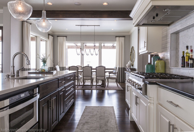 Kitchen with dark stained island. Island is stained in a dark finish with a white quartz countertop. Glass pendants by Kichler Lighting. Kitchen island. Kitchen with dark stained island. #Kitchen #darkstainedisland Restyle Design, LLC.