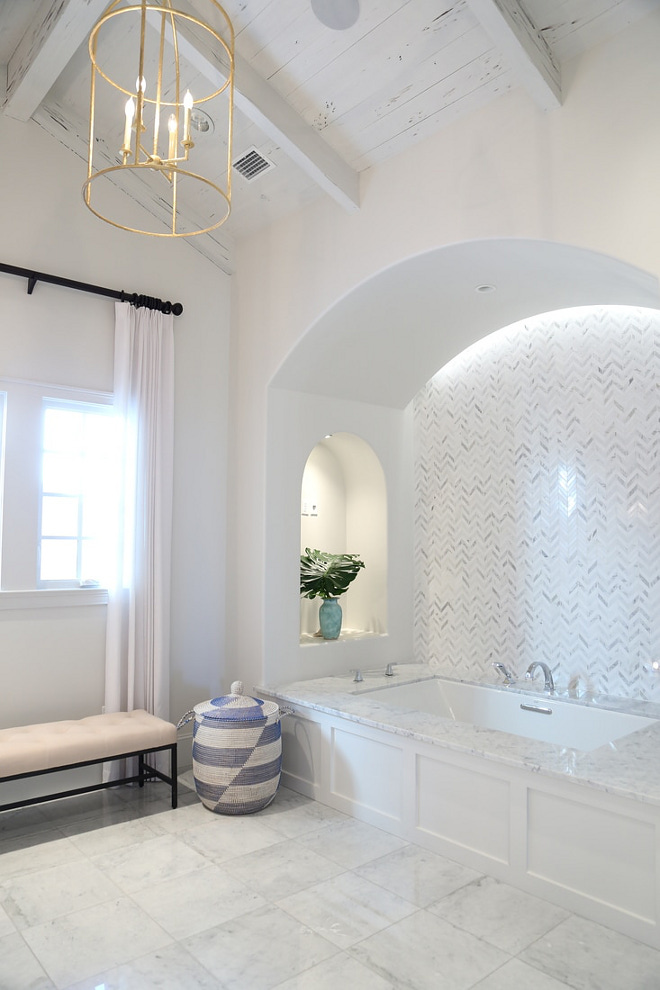 Tub Nook. Arched Bathtub Nook with marble herringbone backsplash tile. Ceiling features rustic Pecky Cypress Wood. Paint Color is Benjamin Moore White Dove. #TubNook #Bathnook #bathroom #ArchedBathtubNook #archednook #marbleherringbonebacksplashtile #herringbonebacksplashtile #Ceiling #rusticwoodceiling #PeckyCypress #Woodceiling #PaintColor #BenjaminMooreWhiteDove Old Seagrove Homes