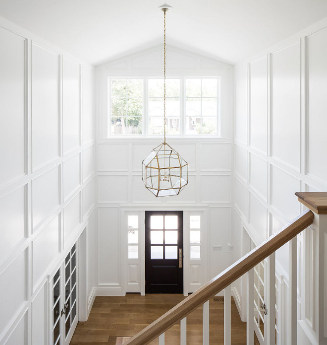 White foyer paneling painted in Simply White by Benjamin Moore. Black door. Lighting is Suzanne Kasler Morris Lantern in Gilded Iron with Clear Glass. White foyer paneling painted in Simply White by Benjamin Moore and Black door #Whitefoyer #foyerpaneling #SimplyWhitebyBenjaminMoore #Blackdoor #Lighting #SuzanneKasler #MorrisLantern #GildedIron #MorrisLanternClearGlass #MorrisLantern Fox Group Construction