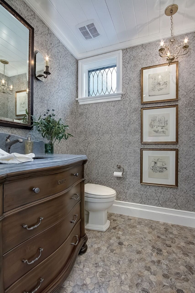 This traditional powder room features a dresser-style vanity and a grey and beige hex marble floor tile. #hextile #powderroom #bathroom Brandon Architects, Inc.