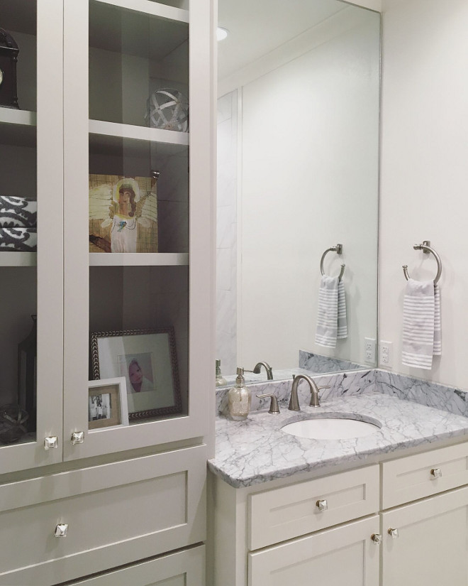 Bathroom Cabinet. This space is small, but everything fits perfectly. I designed the tall cabinet with glass doors and painted in a different color than the vanity so it would appear to be furniture. This cabinet has an outlet for a small lamp and is perfect for showing off decor. The bottom drawers hold pool towels, sunscreen and other pool essentials. #BathroomCabinet Beautiful Homes of Instagram @theclevergoose