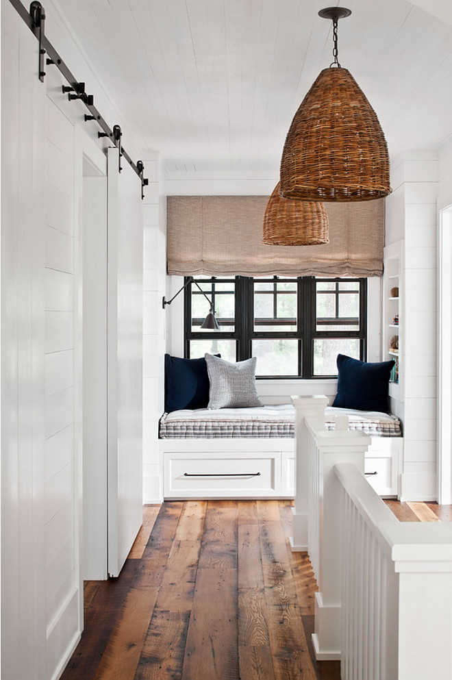 Farmhouse landing with shiplap, window seat reading nook, barn door, basket pendants and rustic wide plank hardwood floor. Farmhouse landing with shiplap, window seat reading nook, barn door and rustic wide plank hardwood floor #Farmhouse #farmhouselanding #shiplap #windowseat #readingnook #barndoor #rusticwide #plankhardwoodfloor #basketpendants Jennifer Worts Design Inc