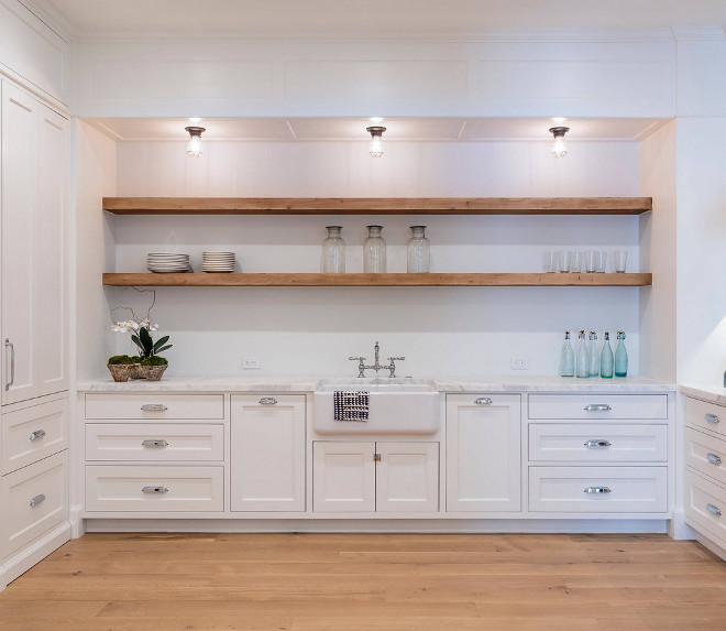 Framed Inset Cabinets with Floating Open Shelves. The laundry room features framed inset cabinets, white oak hardwood flooring and floating open shelves above a farmhouse sink. Countertop is carrara marble. Sleek cabinets Framed Inset Cabinets with Floating Open Shelves. Framed Inset Cabinets with Floating Open Shelves #FramedInsetCabinets #FloatingOpenShelve #OpenShelves #FloatingShelves Haefele Design