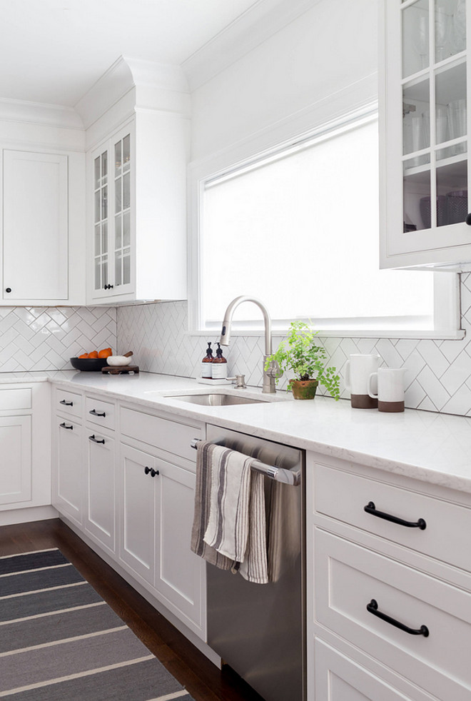 Shaker Kitchen Cabinets with simple herringbone subway tile and white marble countertop. Shaker style cabinets are painted in Benjamin Moore Decorator's White #BenjaminMooreDecoratorsWhite #shakercabinet #shakerkitchen #shakerkitchencabinets #simplebacksplash #backsplash #subwaytile #herringbone #whitemarble Chango & Co.