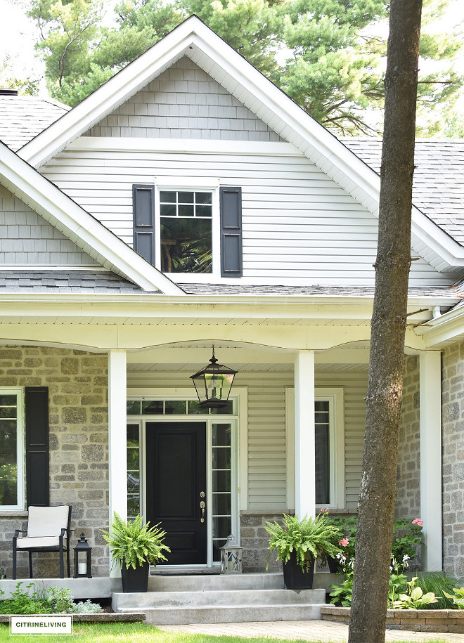 The black front door paint color is Canadian Tire Premier Exterior Paint - Midnight, Semi-gloss. What a timeless paint color #homeexterior #greystone #siding #blackdoor #pendant Beautiful Homes of Instagram @citrineliving Home Bunch