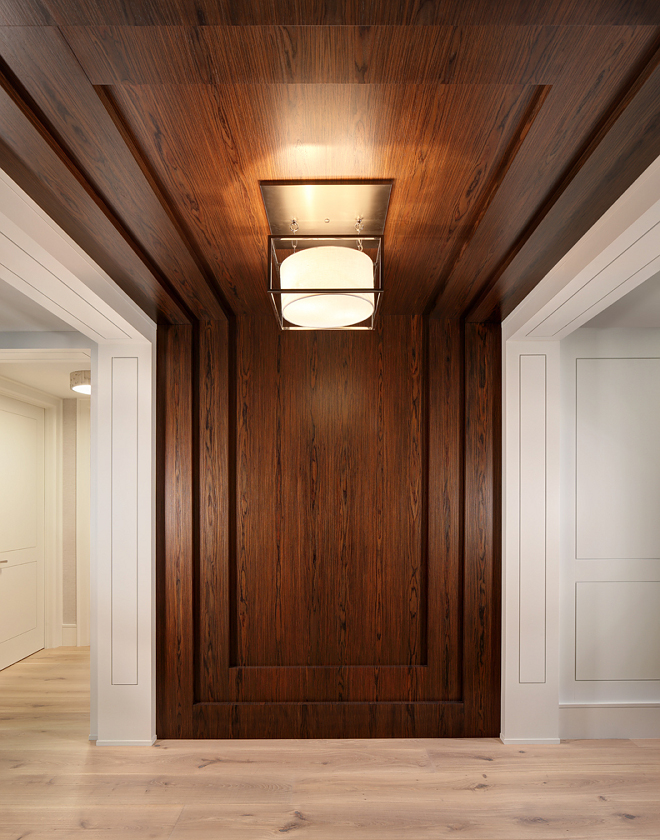 Entry wall paneling. The entry features a modern twist on wall paneling by creating a flush panel detail with a recessed groove. The rosewood feature wall seamless runs up the wall and across the ceiling. Trim/Ceiling Paint: Benjamin Moore OC-17 White Dove. #rosewood #paneling #wallpaneling #entry #foyer W Design