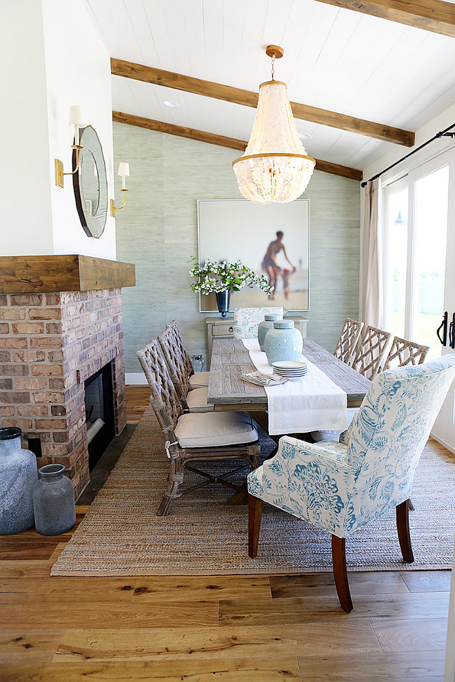 Coastal Dining room with grasscloth wallpaper, brick fireplace and glass chandelier Millhaven Homes. Caitlin Creer Interiors