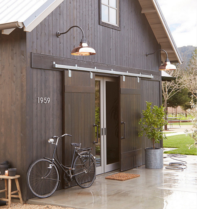 Copper Barn lights. Barn style home with exterior barn doors and copper barn lights. Lighting is Rejuvenation Carson Gooseneck #barnlights #copperbarnlight #barnlighting #exterior #barnlighting #lighting Photo By Rejuvenation