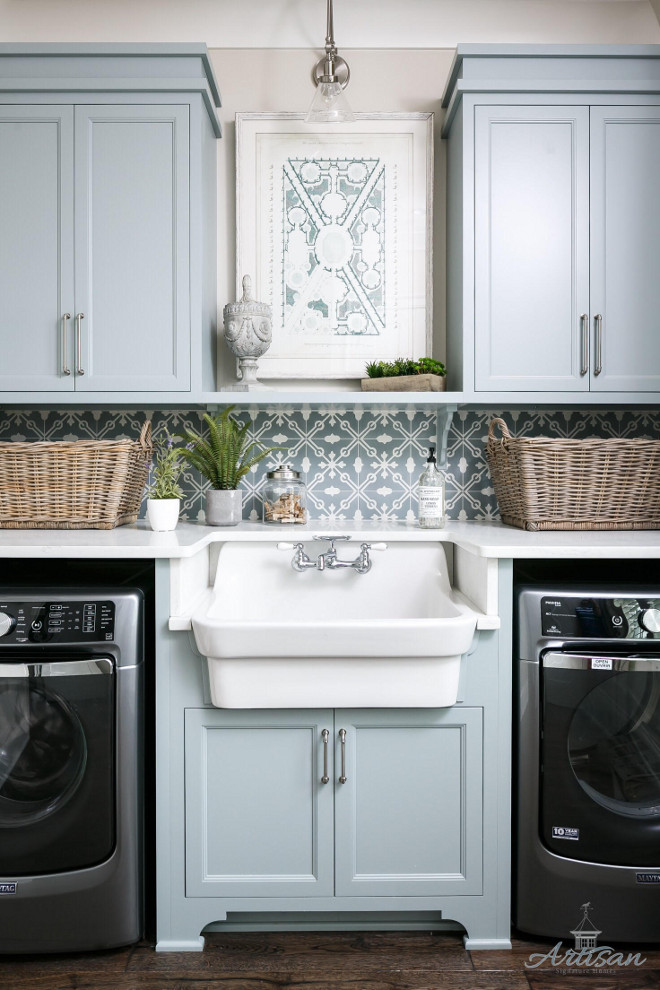 Laundry room farmhouse sink. Laundry room farmhouse sink between washer and dryer. Laundry room with grey blue cabinets, painted in Silver Mink by Benjamin Moore, patterned tile backsplash and farmhouse sink #laundryroom #farmhousesink Artisan Signature Homes