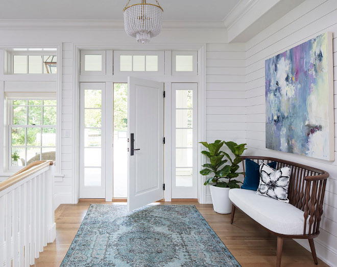 White foyer with white shiplap, white oak hardwood floors and white front door with sidelights. An original art and a blue foyer rug brings some color to this white space. White foyer with white shiplap, white oak hardwood floors and white front door with sidelights. An original art and a blue foyer rug brings some color to this white space. White foyer with white shiplap, white oak hardwood floors and white front door with sidelights. An original art and a blue foyer rug brings some color to this white space #Whitefoyer #whiteshiplap #shiplap #whiteoak #hardwoodfloors #whitefrontdoor Martha O’Hara Interiors