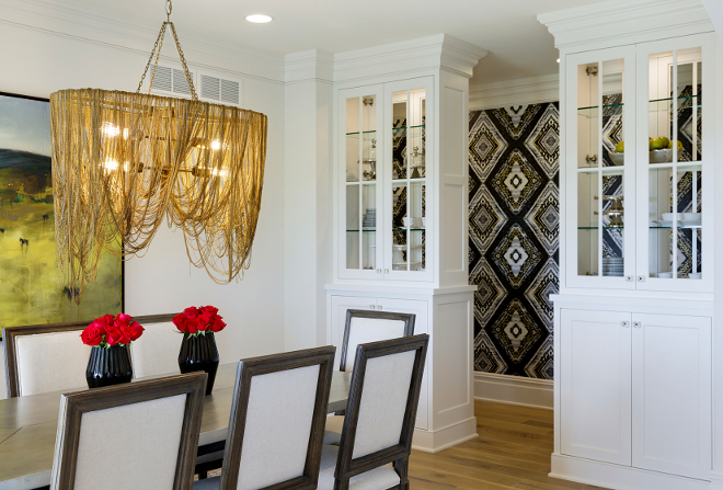 Dining room features a brass chandelier and built in cabinets The dining room features custom designed glass hutches, panel molding accent wall and a chandelier dripping with mixed metal chains