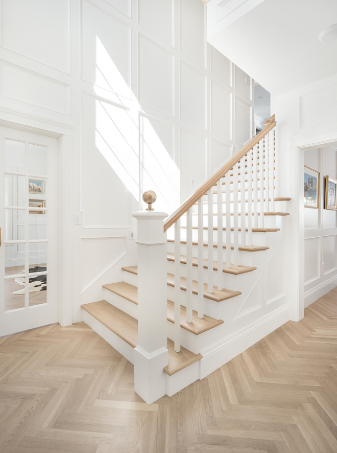 Foyer wall paneling and herringbone hardwood floor Crisp white foyer painted in Benjamin Moore Simply White with classic paneled walls and herringbone hardwood floors #BenjaminMooreSimplywhite #paneling #foyer #herringbonefloors