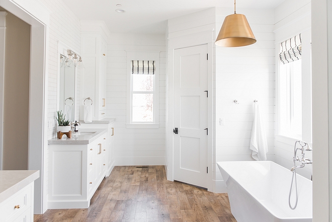 White bathroom with brass lighting and brass hardware