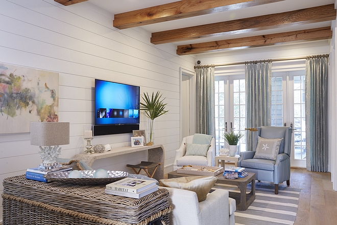 Coastal family room feels relaxed and very beach-y. Notice the wide plank hardwood floors, ceiling beams and shiplap walls
