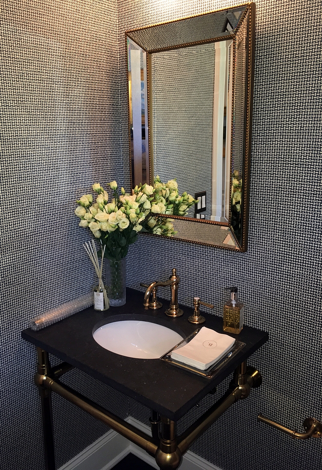 Powder room This powder room features a textured wallpaper and brass fixtures, including a brass washstand with black granite countertop