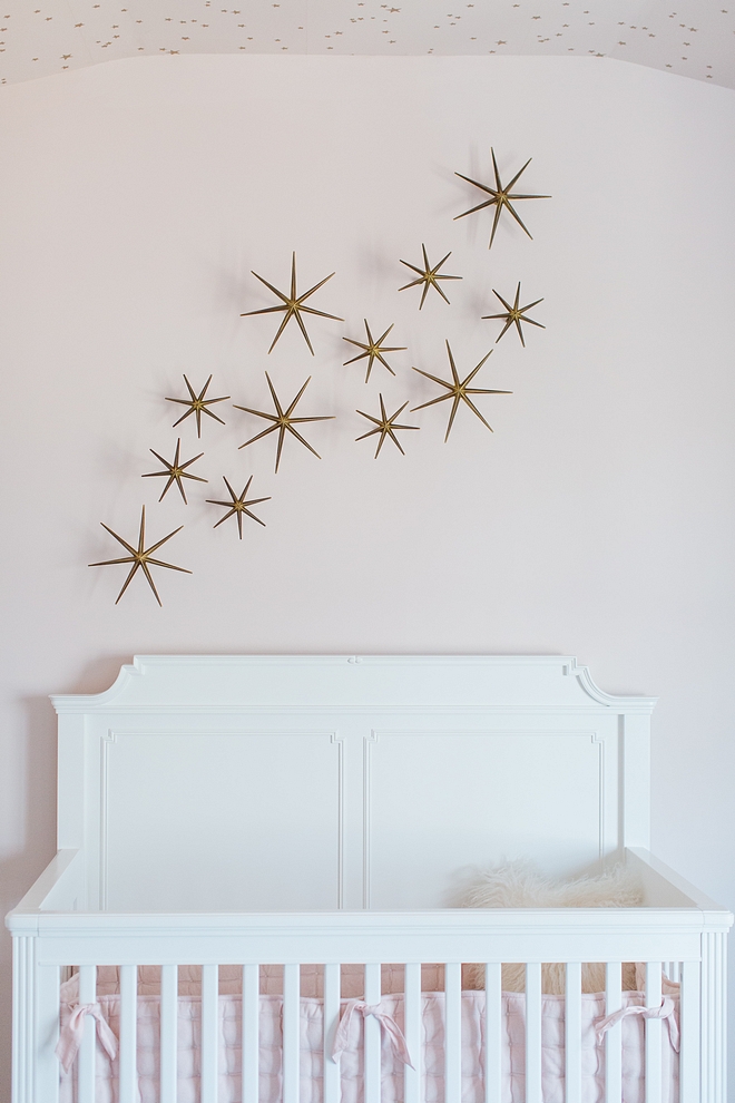 Pale pink nursery with white crib, Stone & Leigh Built To Grow Crib, and metal star wall decor