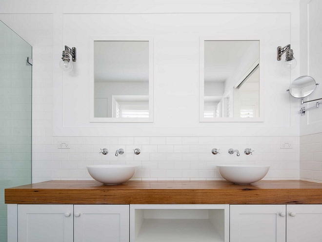 Round bathroom vessel sinks on top of thick wood countertop - clean timeless look