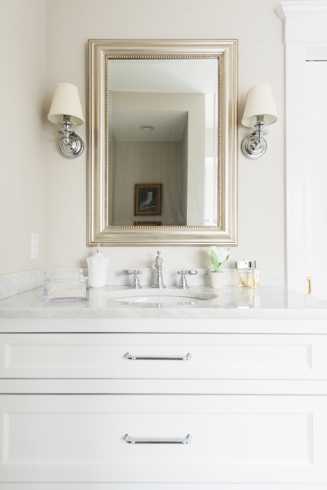 Classic white bathroom vanity with white marble countertop polished nickel hardware and polished nickel sconces flanking mirror