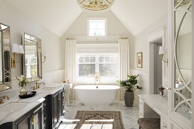 Bathroom The designer appointed this room with grandeur by nestling the master bathroom within the home’s peaked roofline Beside the makeup vanity we designed custom storage with a mirrored finish and curved detailing #bathroom