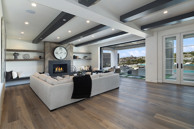 Basement Family Room with reclaimed wood chevron shiplap fireplace, ceiling beams and white oak hardwood flooring