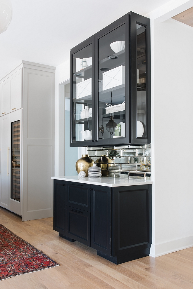 Kitchen Hutch The kitchen hutch features three-sided glass cabinets, quartz countertop and antique mirrored subway backsplash The white decor brings some contrast to the black cabinets #kitchen #hutch