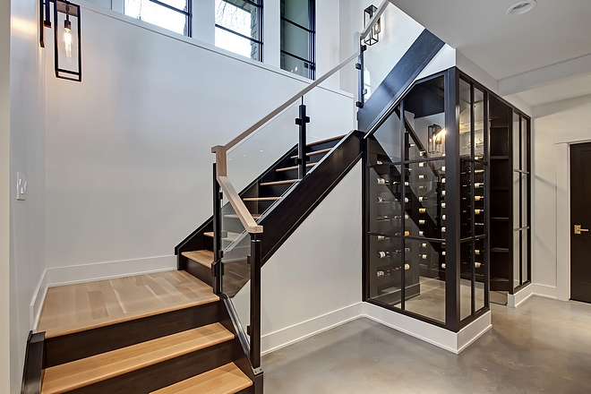 Basement Modern Staircase leading to a wine enclosure with black steel doors #modernstaircase #wineenclosure
