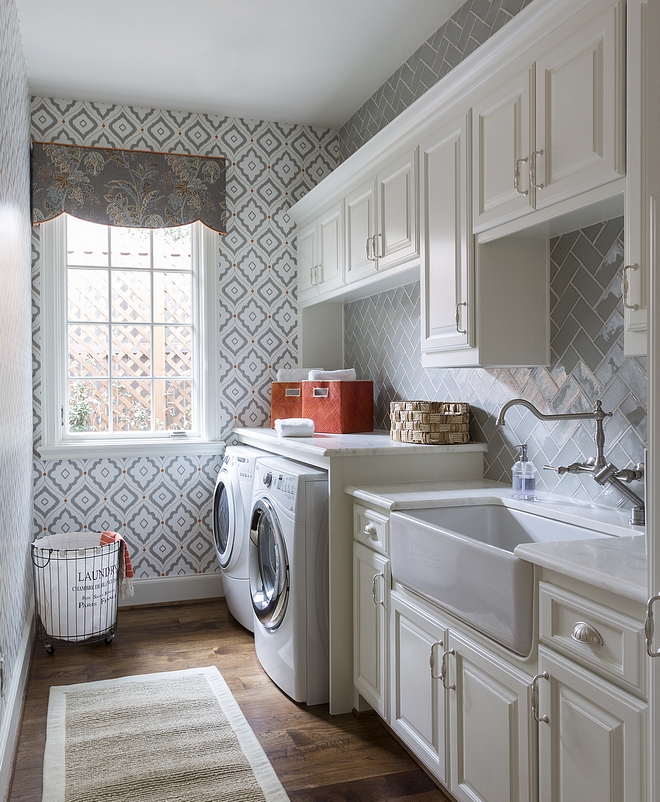 Laundry Room Sherwin Williams Alabaster Laundry room features off-white cabinets, painted in Sherwin Williams Alabaster SW 7008, hardwood floors, white marble countertop, farmhouse sink and a grey backsplash tile in herringbone pattern #laundryroom #SherwinWilliamsAlabaster