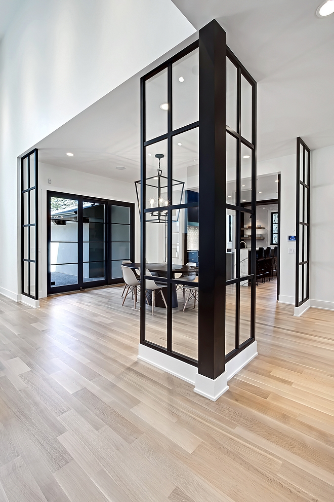 The breakfast nook features glass and lacquered dividers This space is viewed right when you walk into the home and the designer defined the space with these custom dividers #interiorideas #interiordesignideas #roomdividers #blackandwhite #blackwindows
