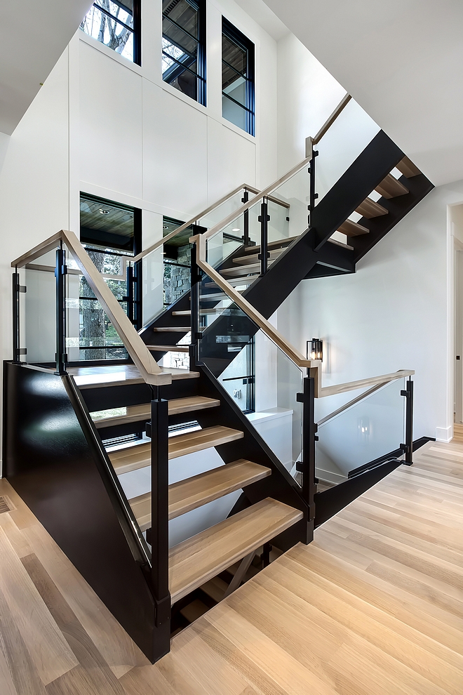 Modern Staircase The staircase is a combination of custom iron post in a matte black finish, 10 mm glass panels and a 1/4 sawn oak handrail. It goes perfectly with the black stringers and natural finish hardwood treads Custom designed hickory square handrail, iron post & glass panel railing #ModernStaircase #Staircase