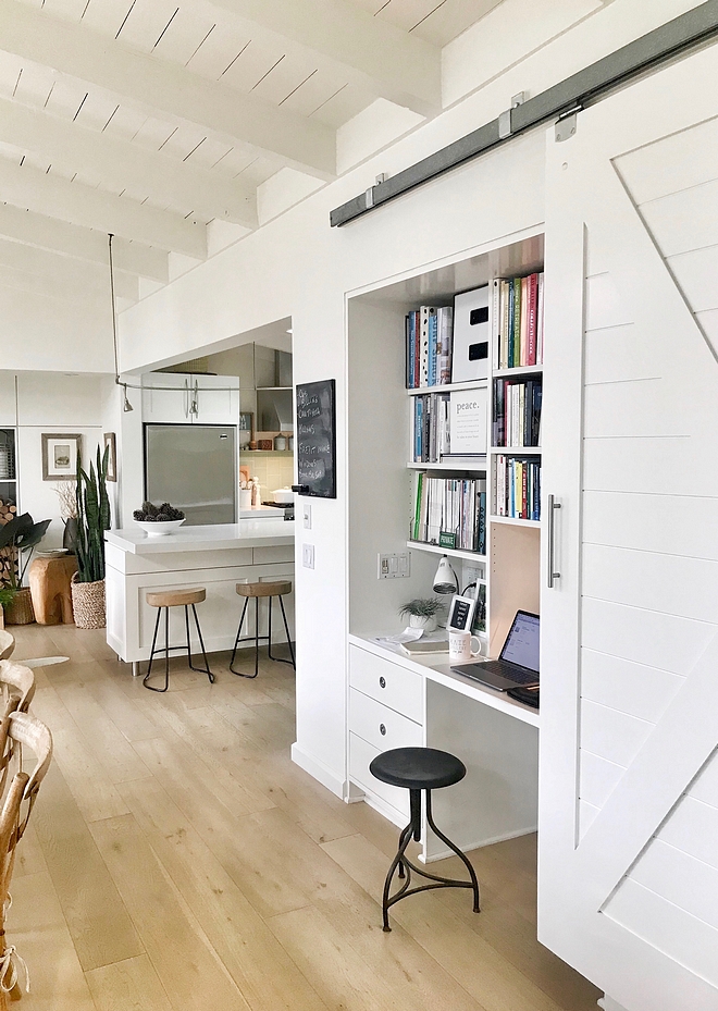 Built in Desk A white barn door conceals a practical built-in desk with built-in bookshelves that serves as the main home office Small Spaces Small Interiors #barndoor #builtindesk #builtins #smallspaces #samllinteriors