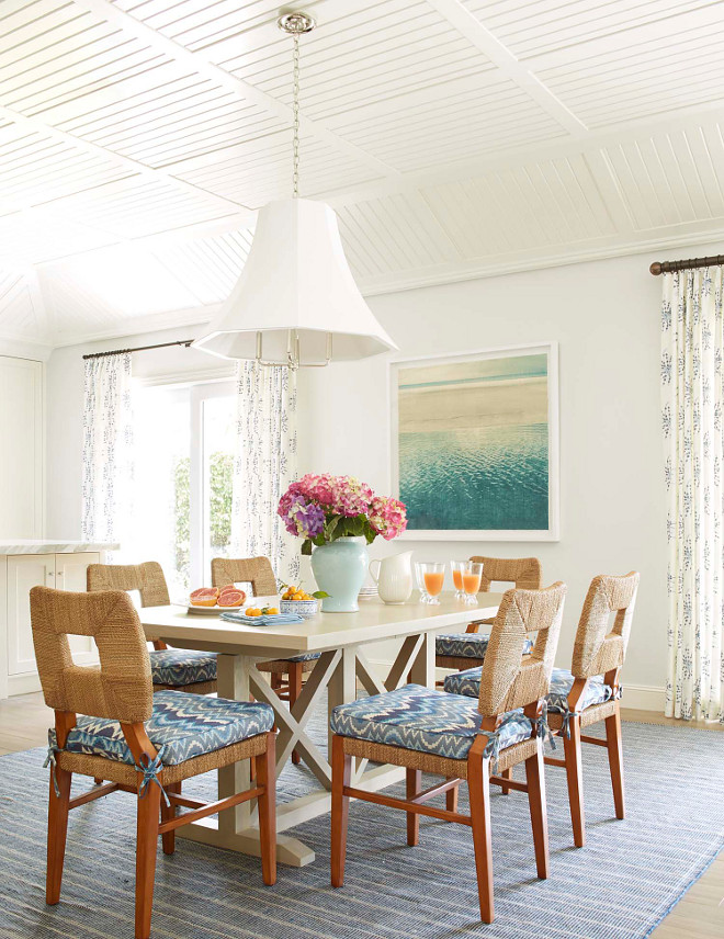 Coastal Dining Room with off white walls, painted in Paper White by Benjamin Moore, striped blue rug, light wood dining table and paneled ceiling vaulted tongue-and-groove ceiling #CoastalDiningRoom #offwhitewalls #PaperWhitebyBenjaminMoore