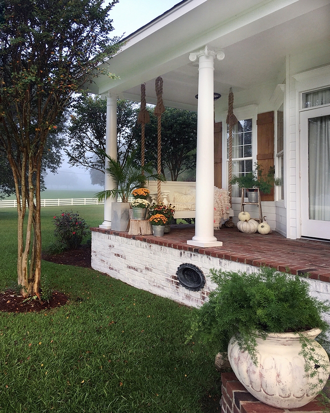 Country home with front porch with swing and brick flooring