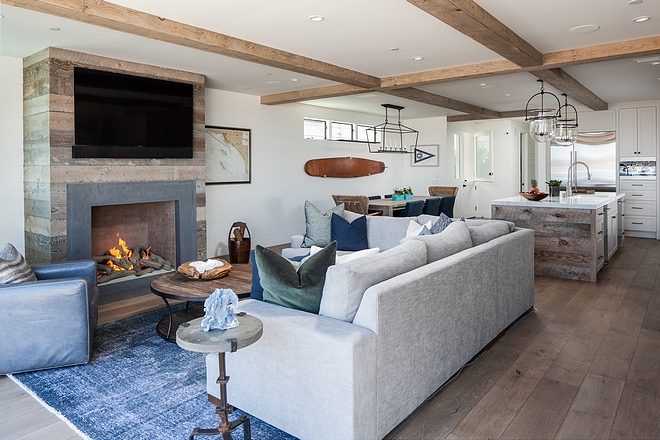 The living room features a fireplace with reclaimed plank boards Ceiling treatment is a combination of drywall and reclaimed wood wrapped false beams #fireplace #reclaimedboards #reclaimedwood #reclaimedplanks #falsebeams