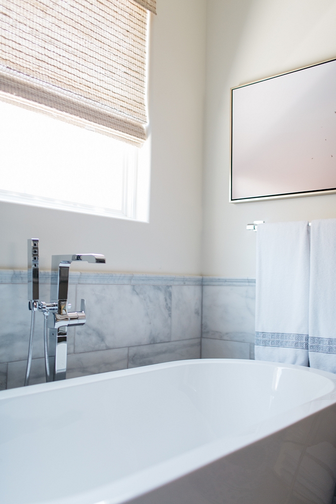 The sleek tub is bordered with large format marble tiles. The marble tiles are laid horizontally for a polished feel. For another special detail, we capped the large wall tile with a chair rail. It adds a nice, finished edge to the space