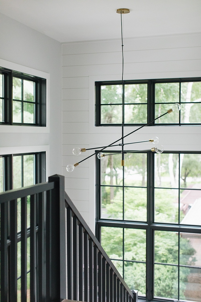 Farmhouse staircase with shiplap paneling, black windows, black railing and a modern mobile chandelier #farmhousestaircase #shiplap #staircaseshiplap #blackwindows #modernchandelier #mobilechandelier