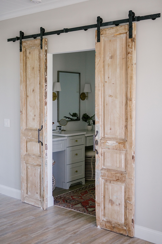 Hung on barn door hardware, these antique doors add personality and architectural interest to this bathroom #bathroom #antiquedoors #barndoor #bardoorhardware