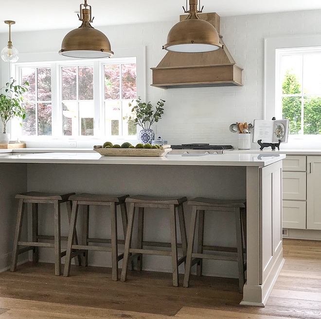 Coastal farmhouse kitchen with no upper cabinets and windows flanking range hood Grey kitchen island and chalk painted subway tile as backsplash #Coastalfarmhouse #kitchen #nouppercabinets #kitchenwindows #rangehood #chalkpaint #backsplash